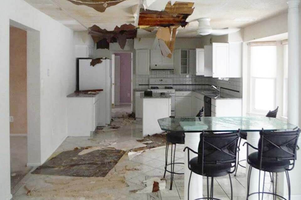 A kitchen with a broken ceiling and a table and chairs.