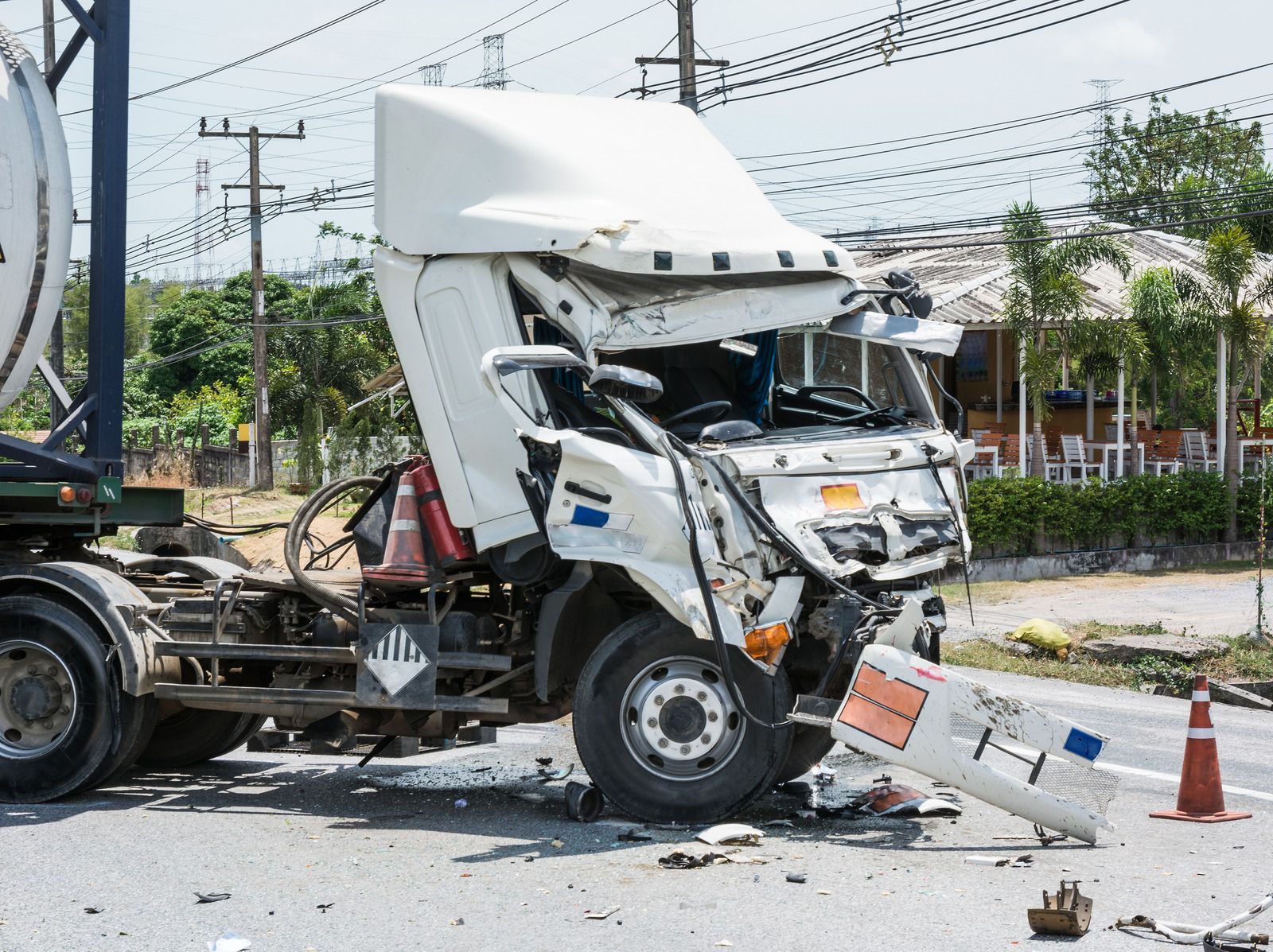 A white semi truck has crashed into another truck on the road.