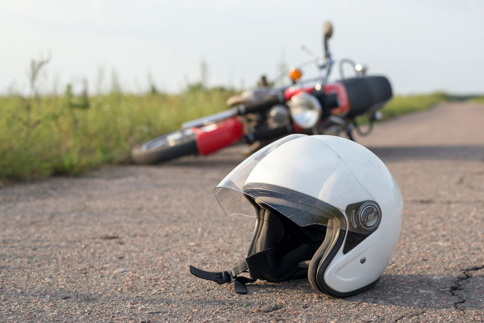 A white helmet is laying on the ground next to a motorcycle.