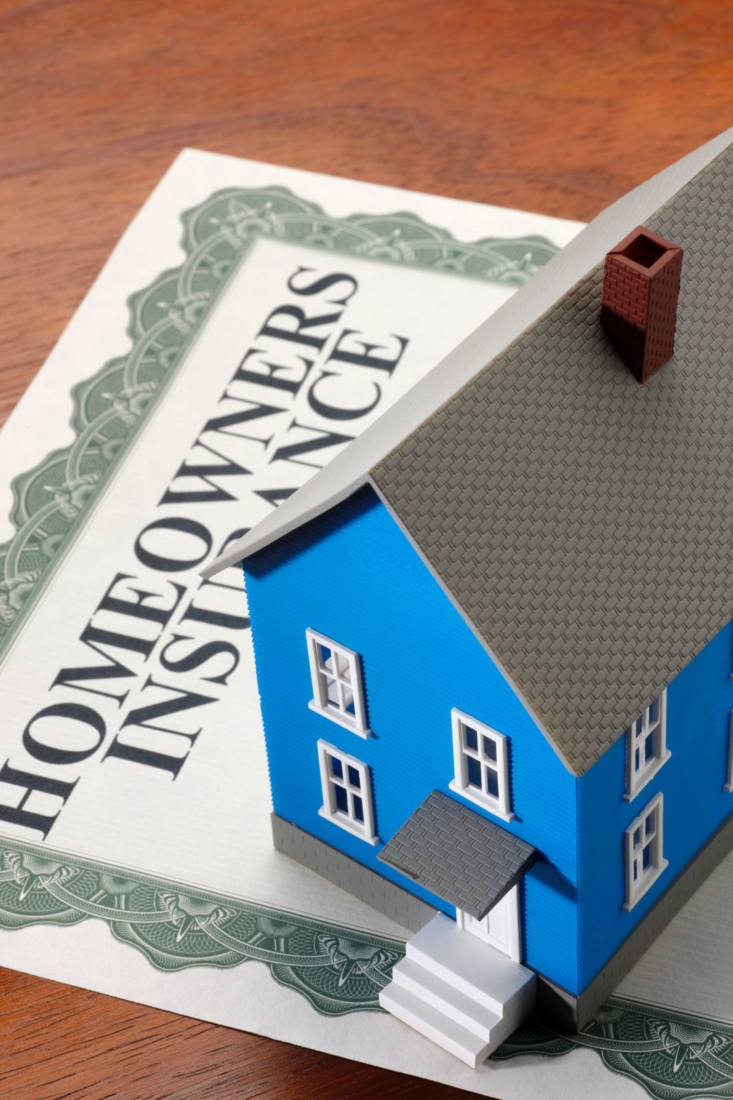 A blue house is sitting on top of a homeowners insurance certificate
