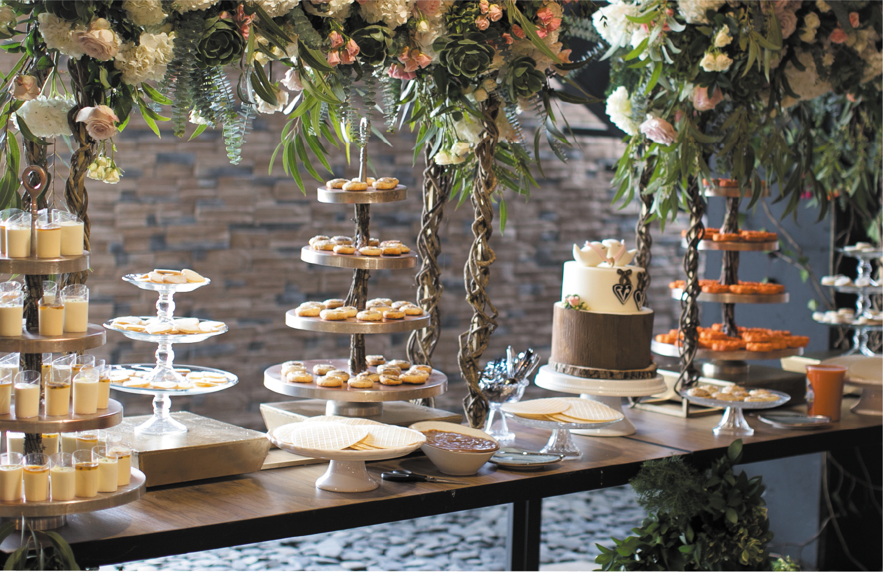 Una mesa llena de muchos postres y arreglos florales.