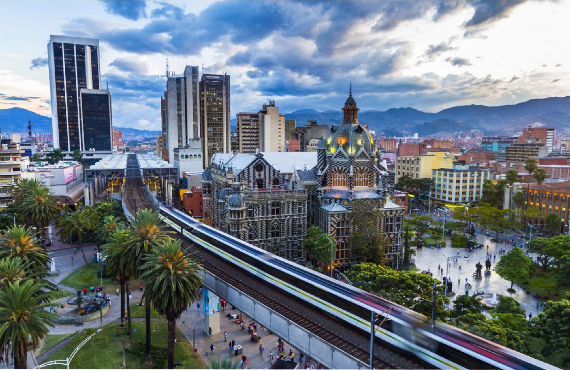 Una vista aérea de medellin ciudad con un tren pasando por ella.