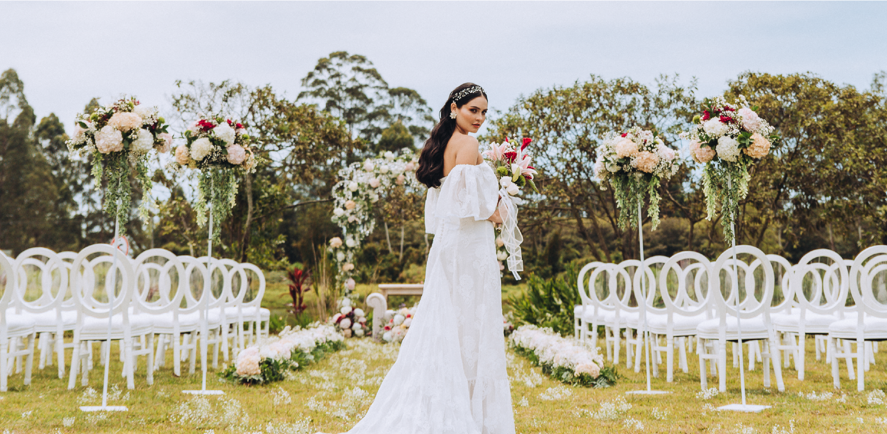 Una novia con un vestido de novia blanco está parada frente a una fila de sillas blancas  hotel Lagoon Llanogrande