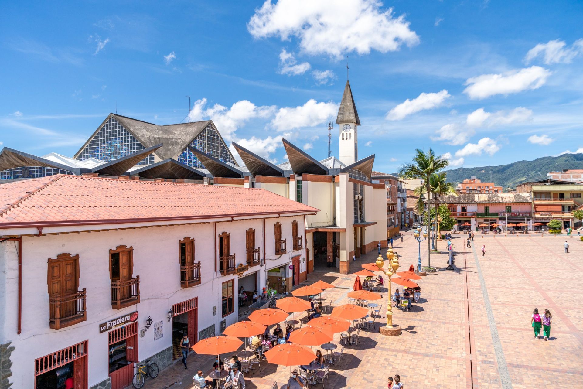 Una vista aérea de una plaza de la ciudad con sombrillas y una torre de reloj carmen del viboral