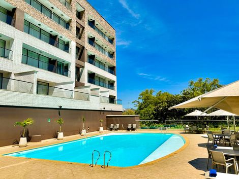 Hay una gran piscina frente a un edificio hotel lagoon llanogrande