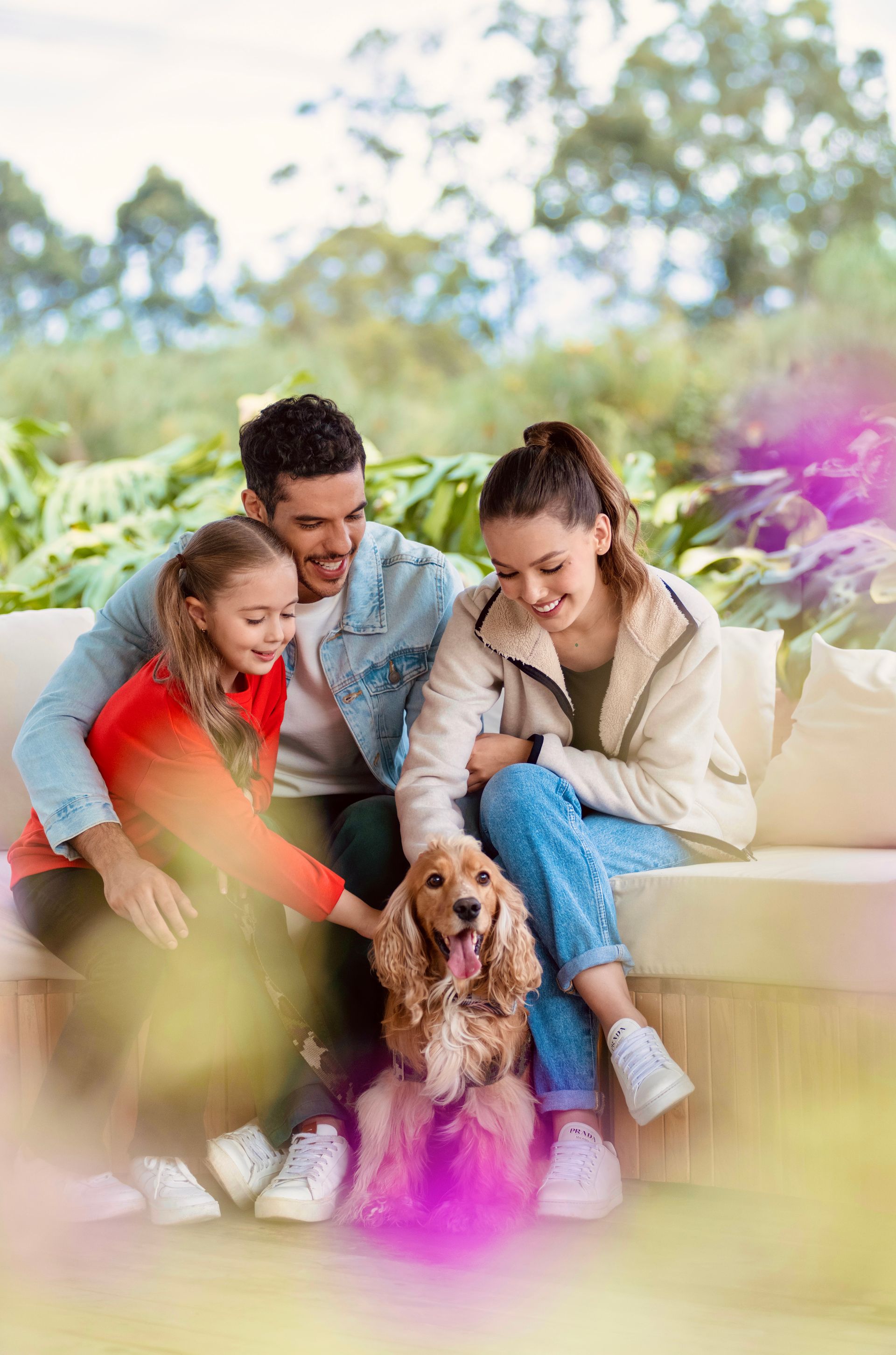 Una mujer sostiene un pequeño perro blanco mientras está sentada en una mesa con una computadora portátil.