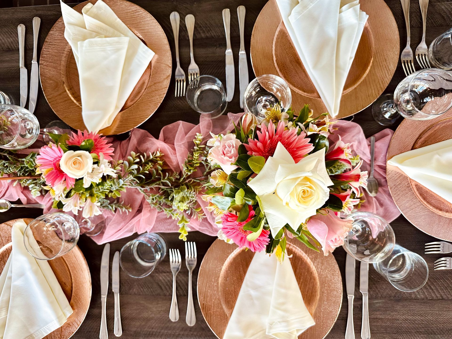 Una mesa preparada para una recepción de boda con platos, servilletas, cubiertos y flores hotel lagoon llanogrande.