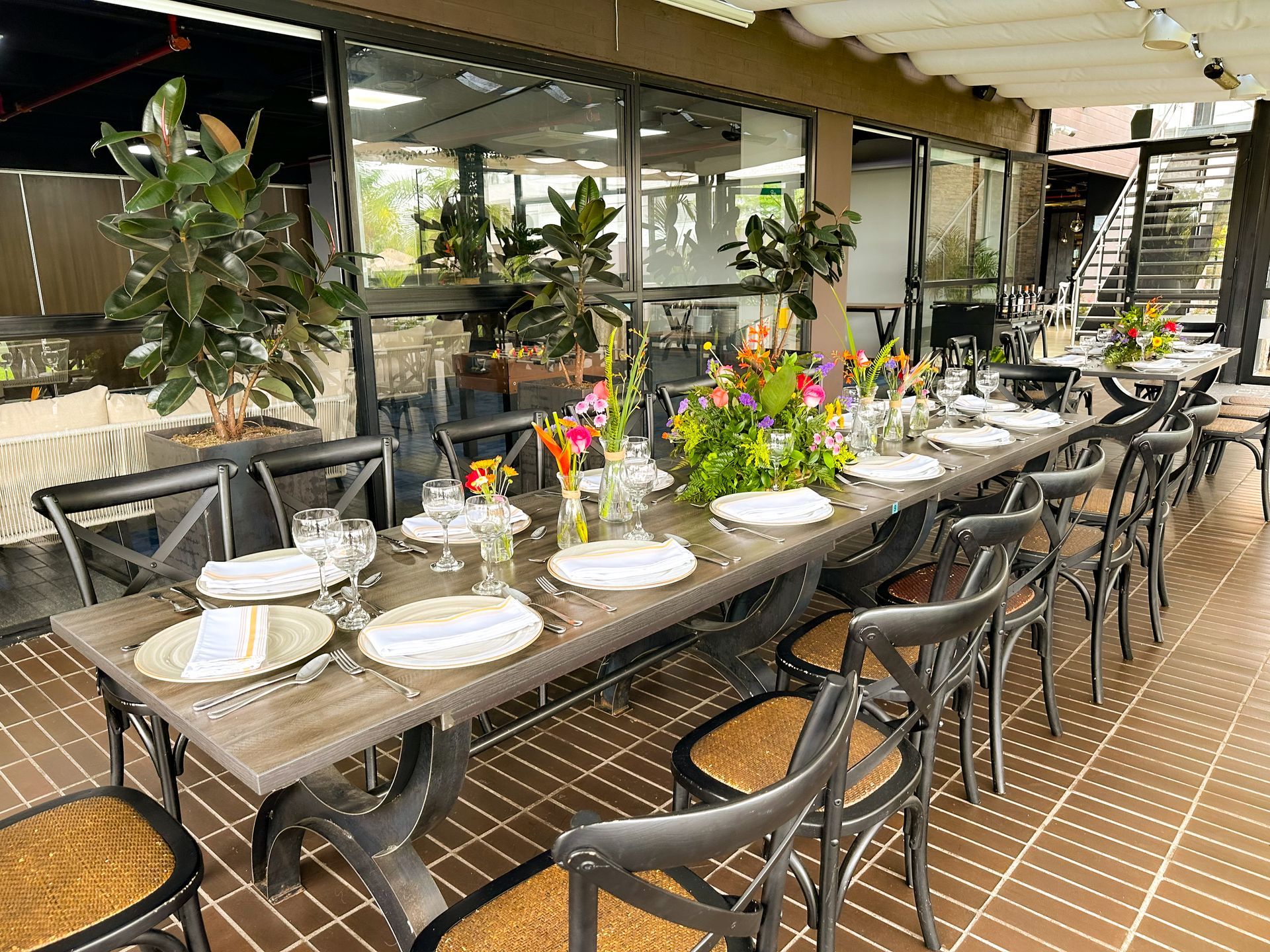 Una mesa larga con platos, vasos y flores en un restaurante hotel lagoon llanogrande.