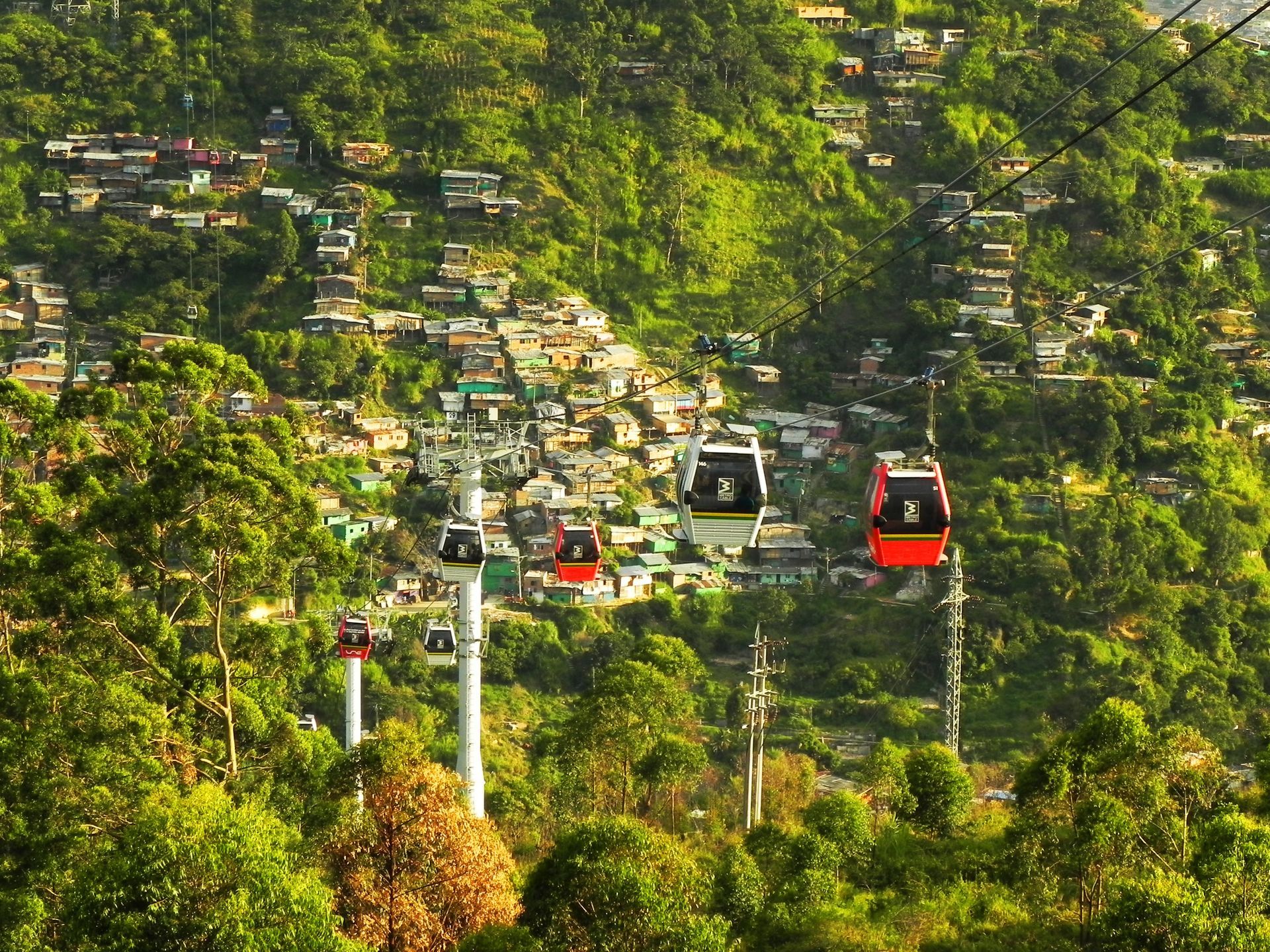 Un teleférico baja por una colina en medio de medellin.