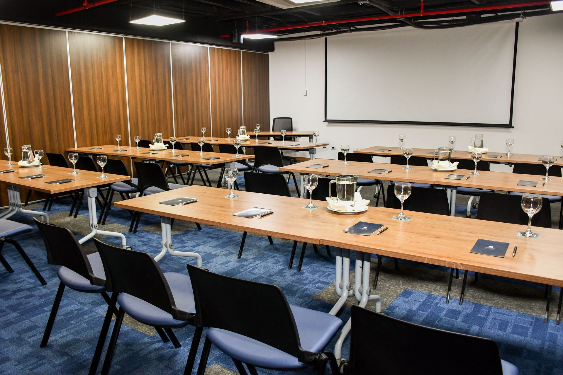 Una sala de conferencias con mesas y sillas y una pantalla de proyección  hotel Lagoon Llanogrande.