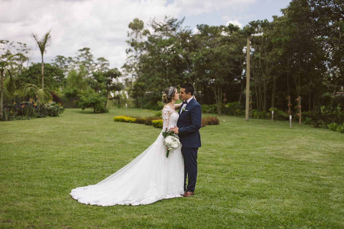 Una novia y un novio están de pie en un campo de hierba  hotel Lagoon Llanogrande.