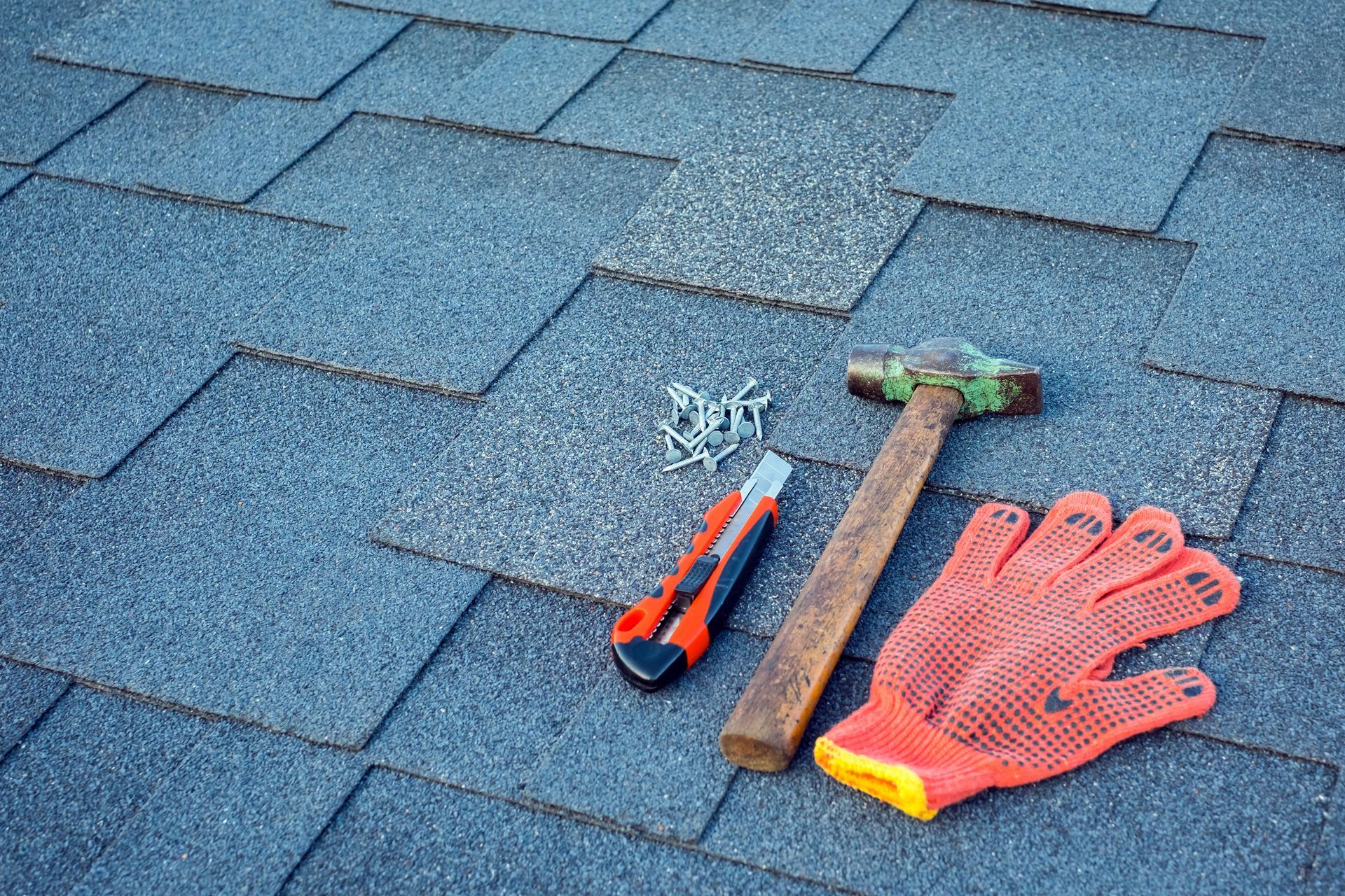 Close-up of asphalt shingles with tools, showcasing residential roofing contractor services.