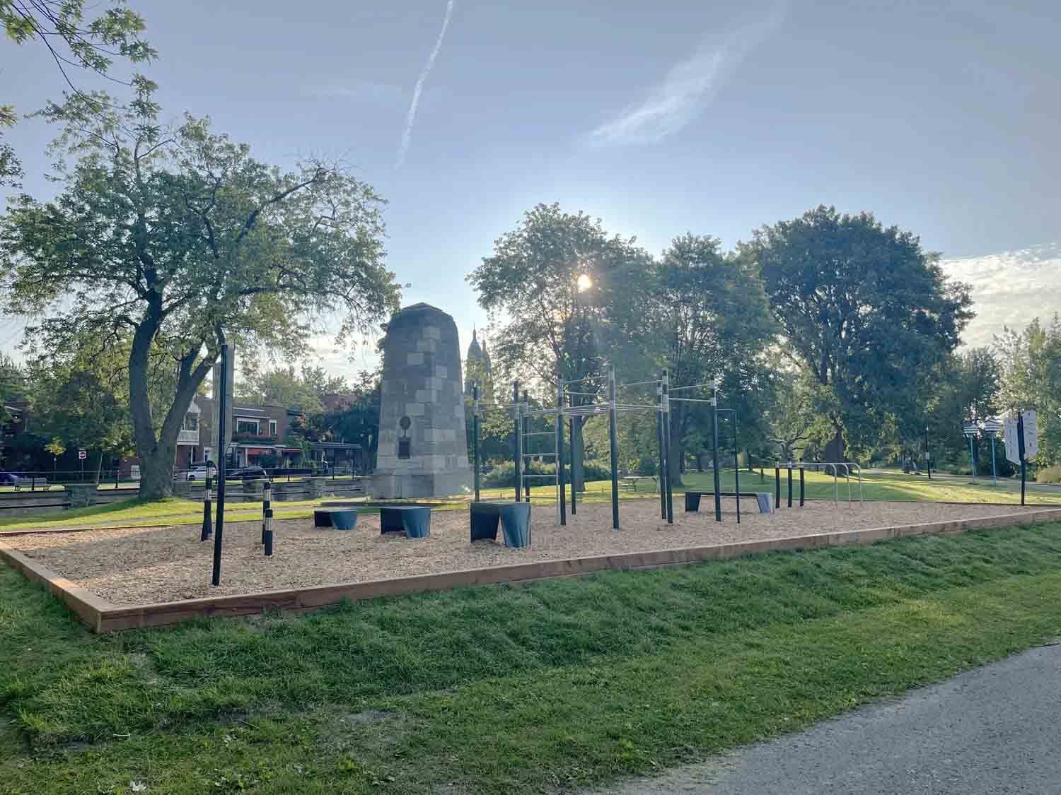 Une pelleteuse orange démolit des gravats de béton devant un bâtiment aux fenêtres cintrées.