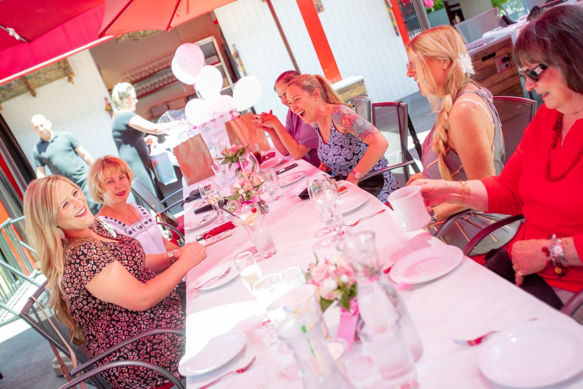 A group of women are sitting at a table with plates and glasses.