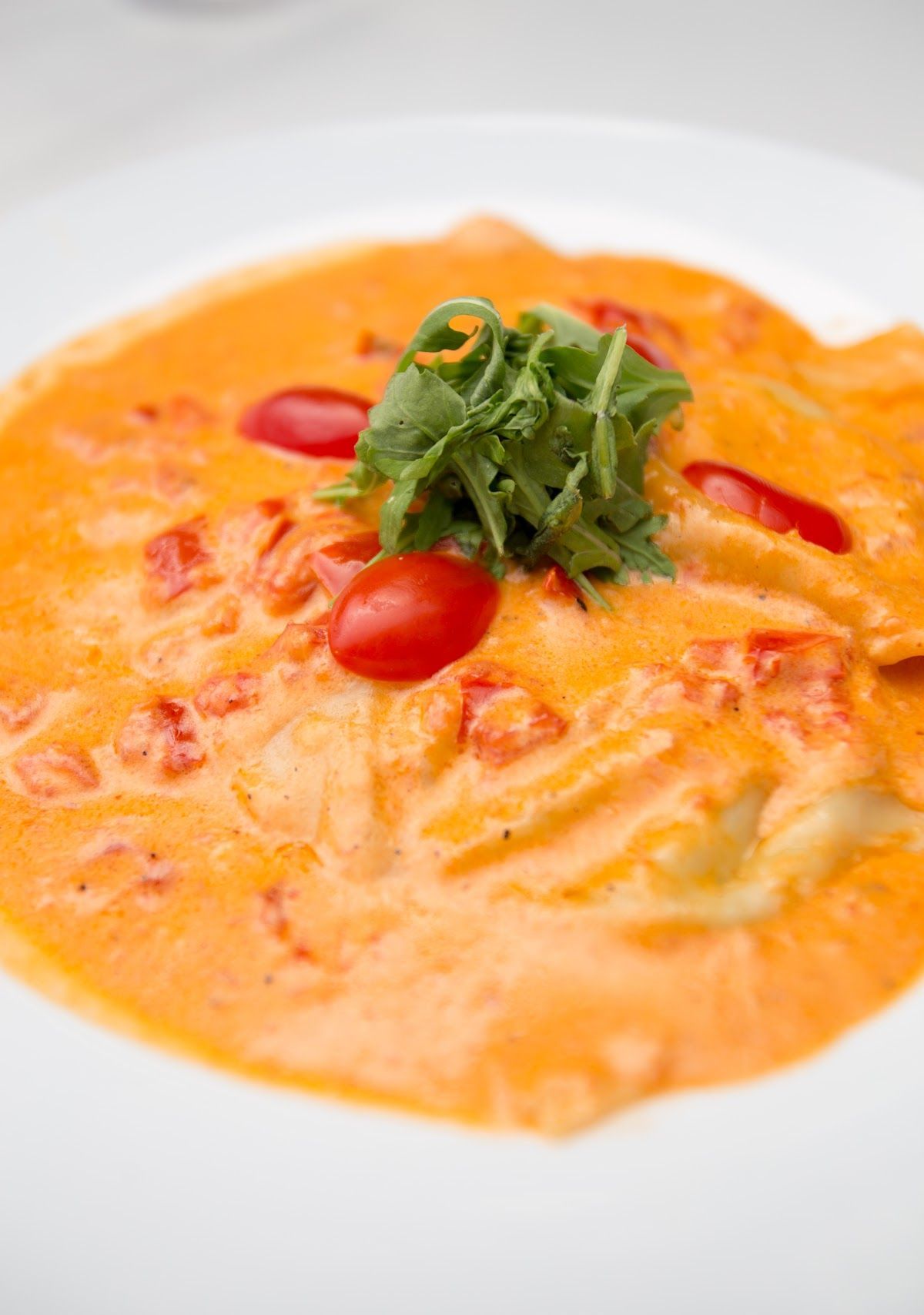 A close up of a plate of food with tomatoes and sauce on a table.