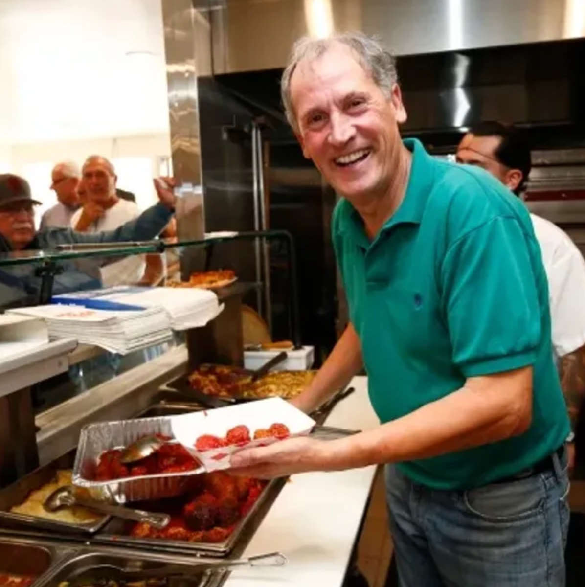 A man in a green shirt is holding a tray of food