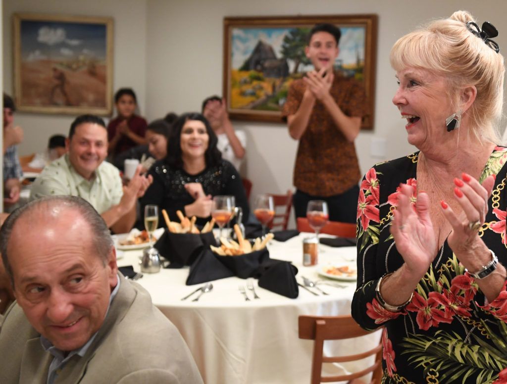 A group of people are sitting at tables in a restaurant applauding