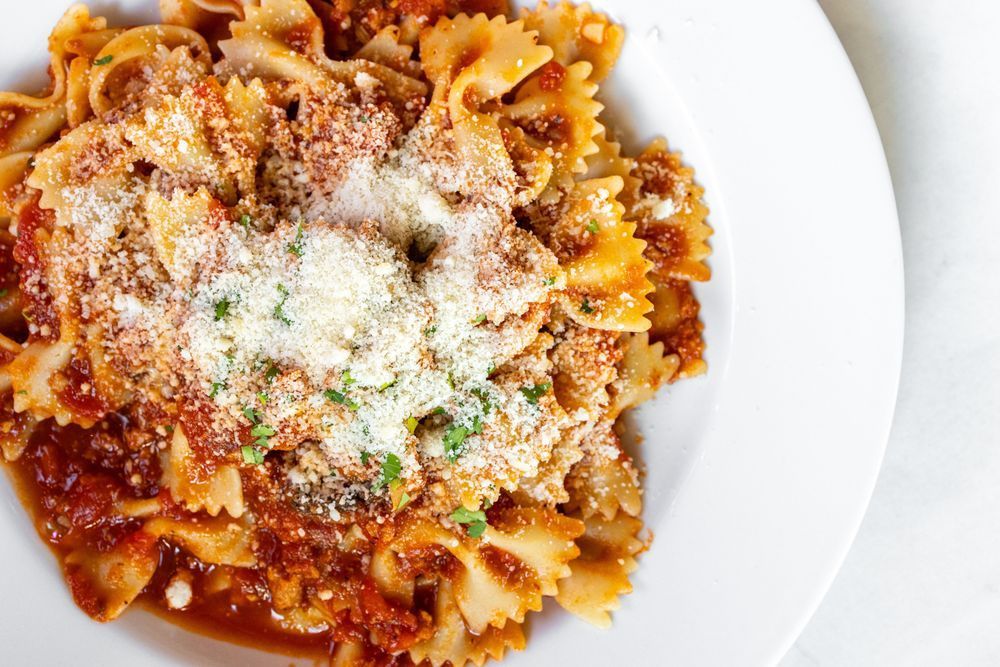A white plate topped with pasta and sauce on a table.