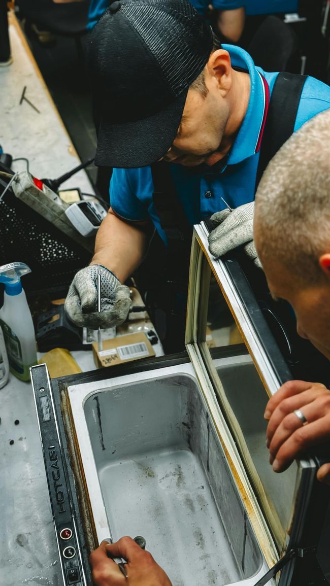Technician working inside an open equipment case, inspecting cables in a workshop setting