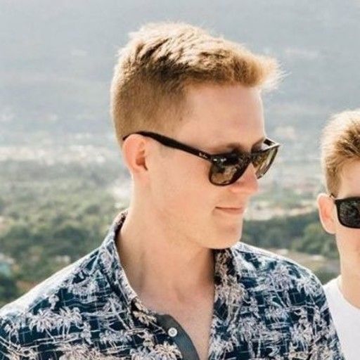 Man wearing a black baseball cap and t-shirt smiles at the camera.