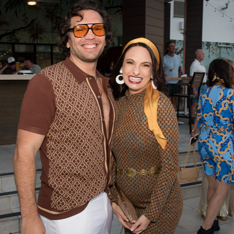 Man smiling widely, looking slightly to the right, against a blue background.