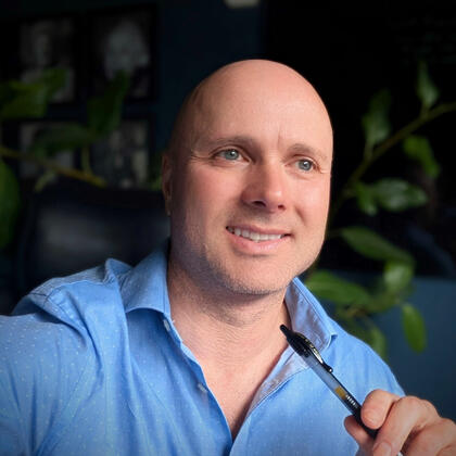 Two men posing for a photo, one wearing a black polo shirt, the other a plaid button-up.