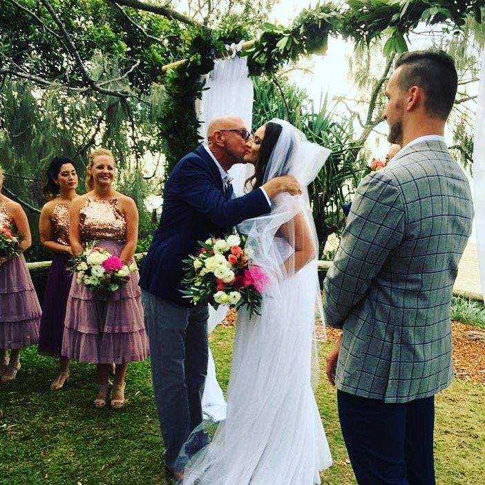 dad kissing daughter wearing veil after walking her down aisle to waiting groom in checked jacket at Noosa Casuarina Grove