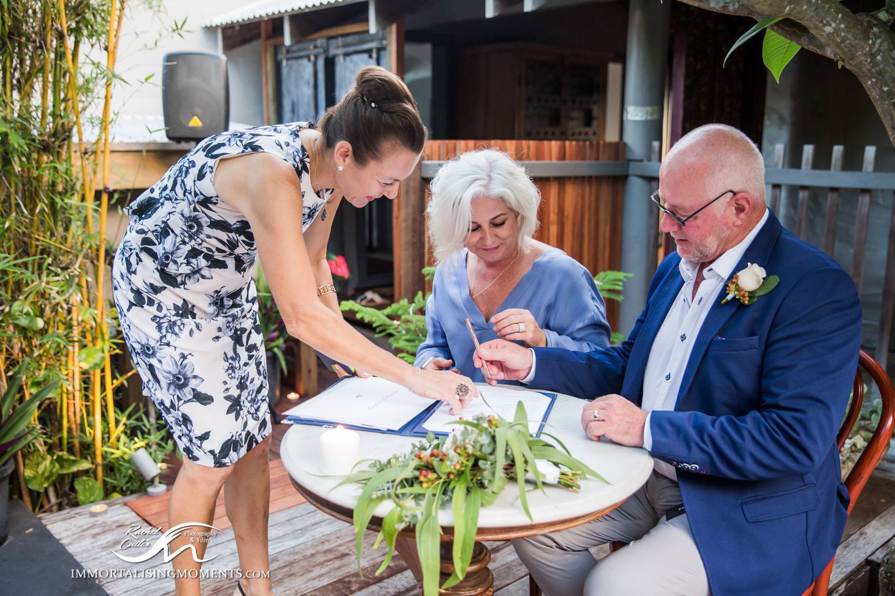 older couple marry at Noosa Airbnb with flowers on table, bride in blue dress, groom in blue jacket