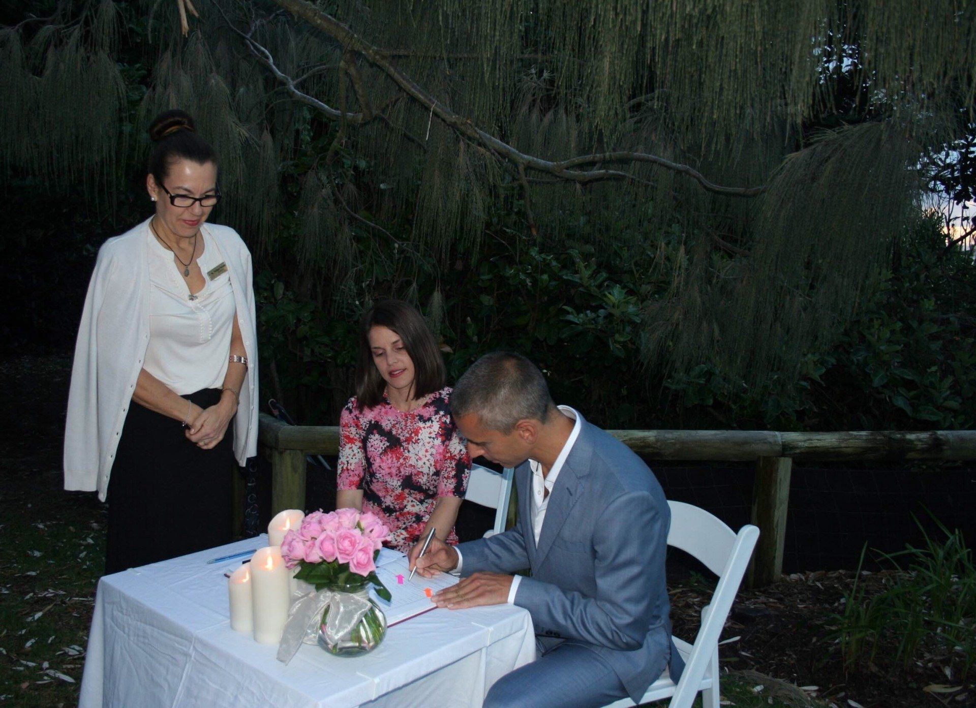 night wedding at Noosa main beach, pink flowers on table and candles , celebrant in black and white