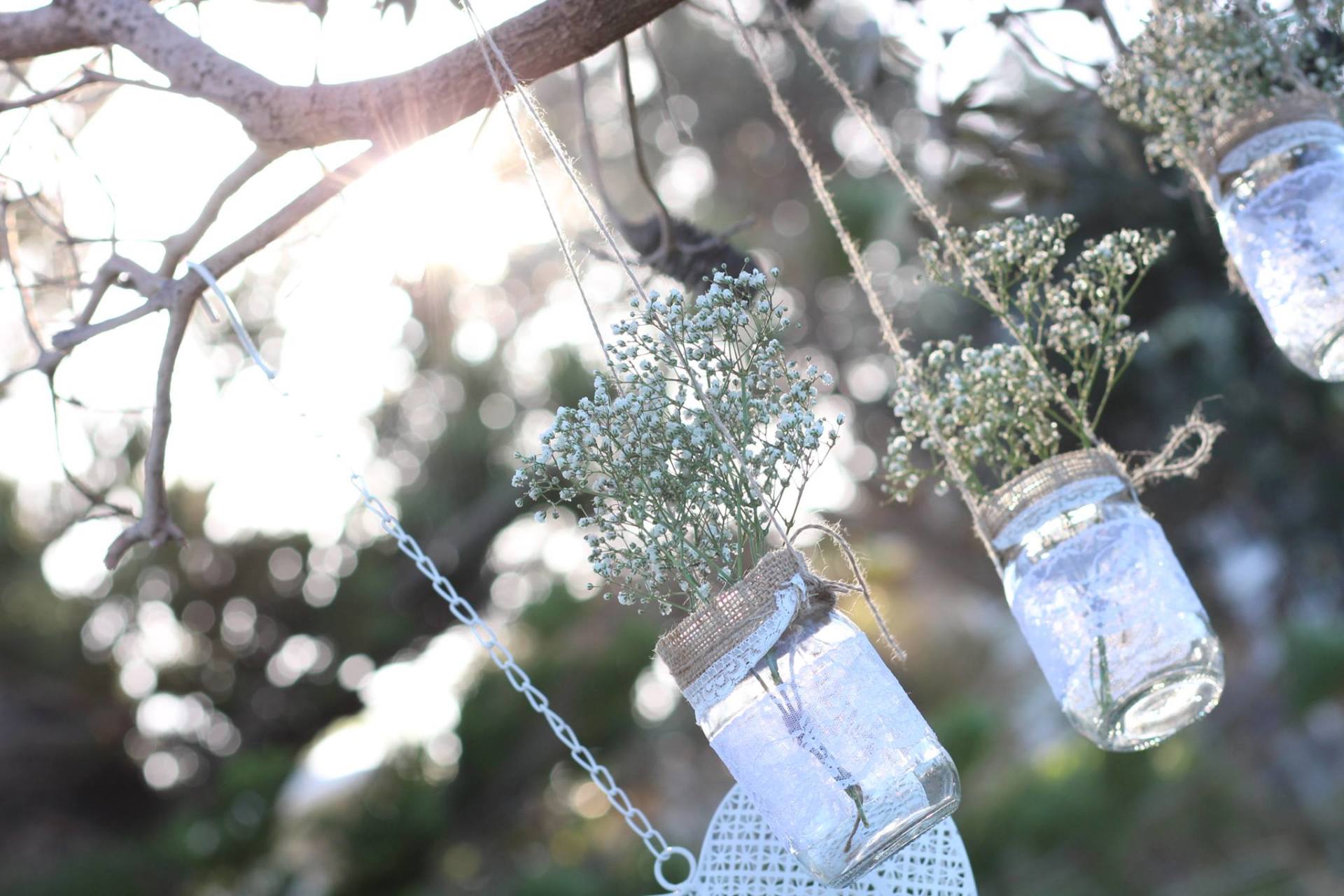 hanging mason jars with white flowers and hearts in the trees