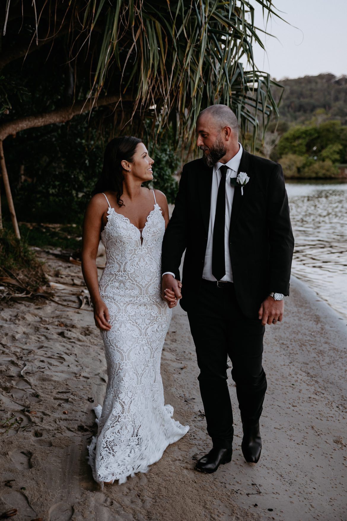 Newlywed couple strolling hand in hand along Noosa Beach, guided by a Noosa Wedding Celebrant – Noos
