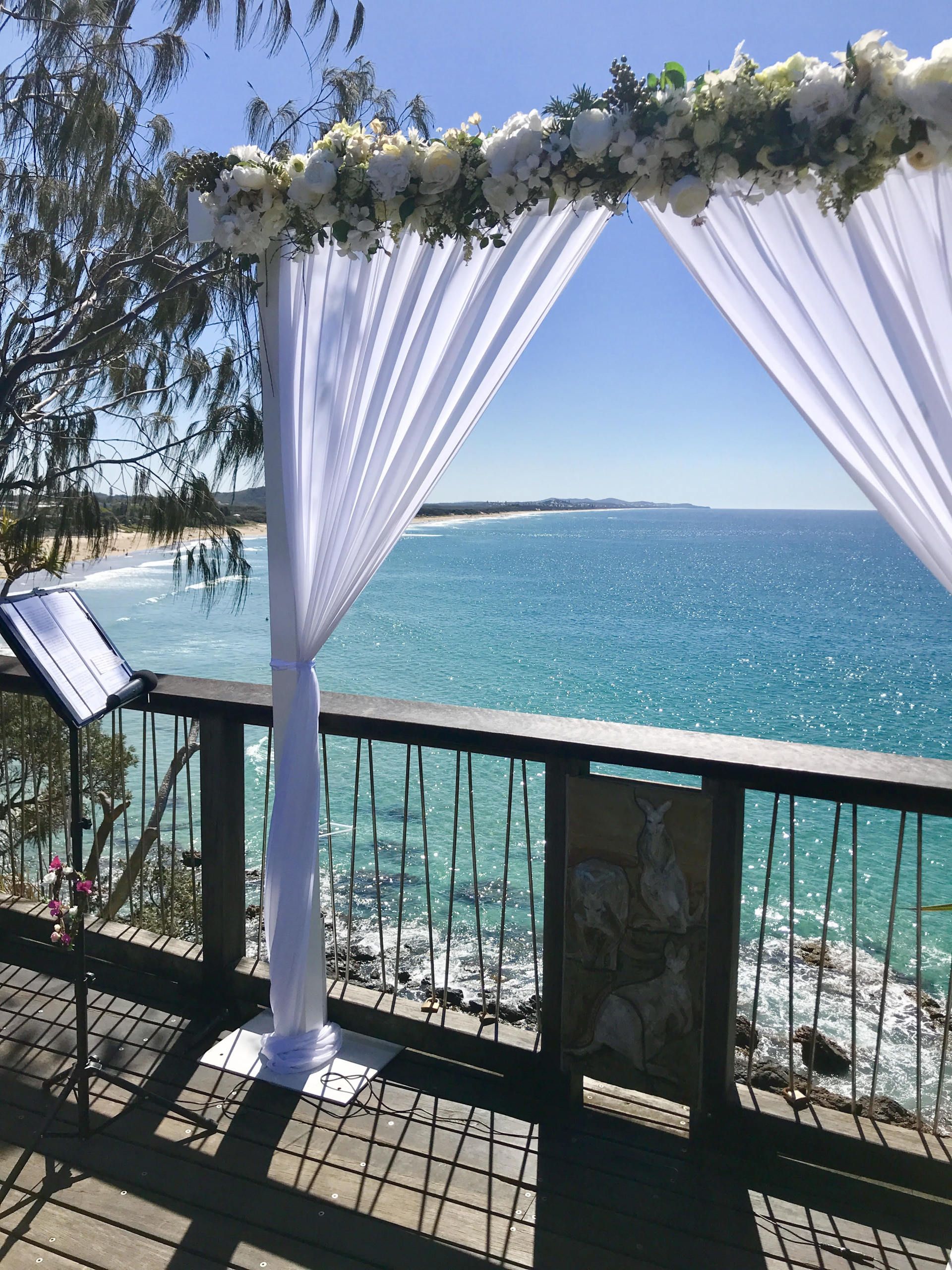 beautiful morning wedding set up with arbor and lectern at Coolum Point Perry with glistening ocean behind