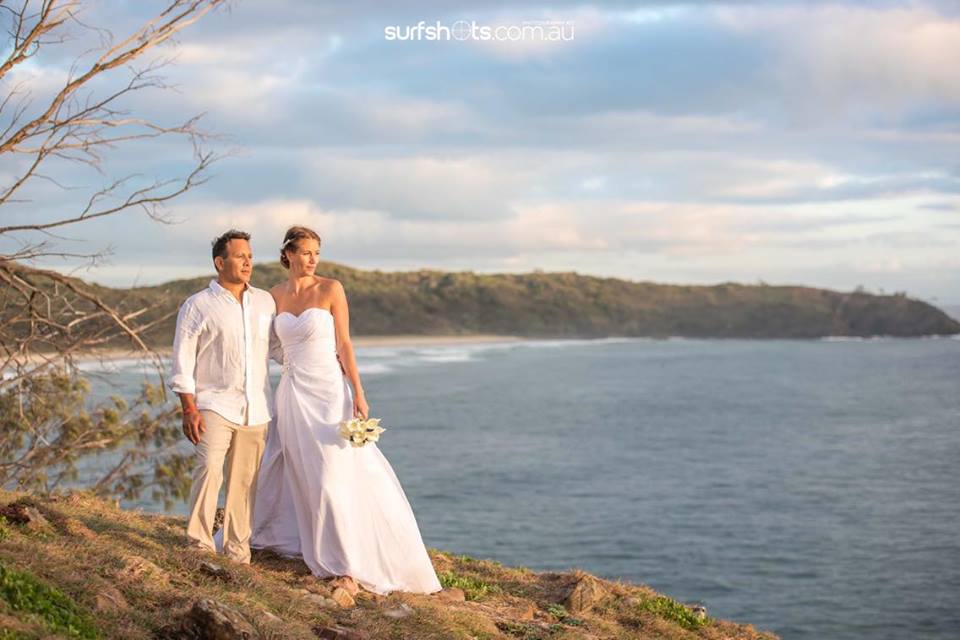 Couple atop a Noosa National Park peak having just eloped, both in white and beige with flowers