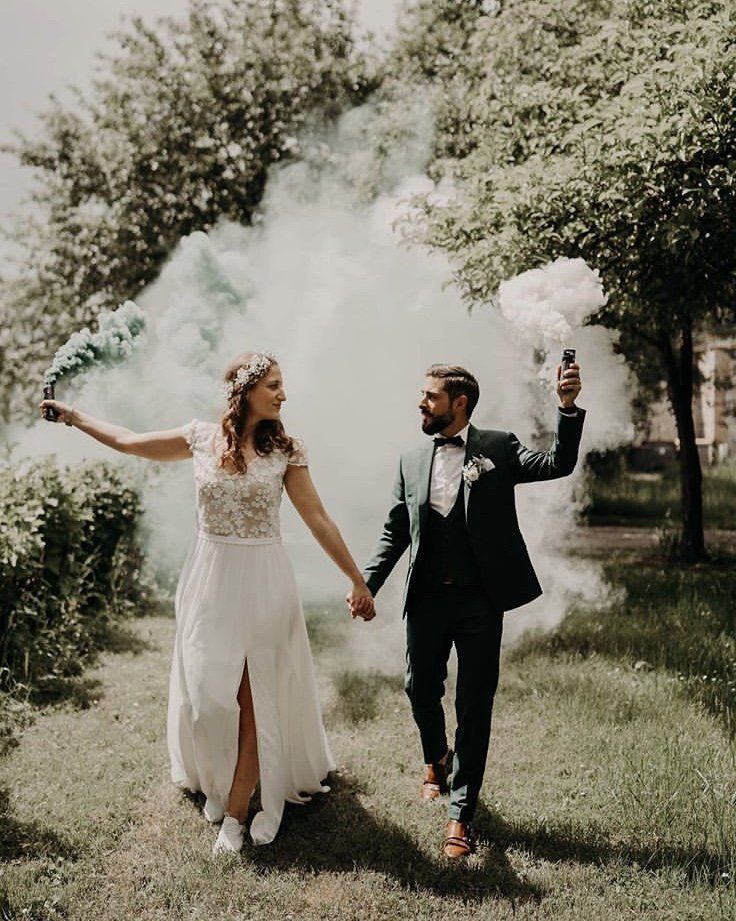 newly married couple after their hinterland wedding holding hands and white and green smoke bomb cannons