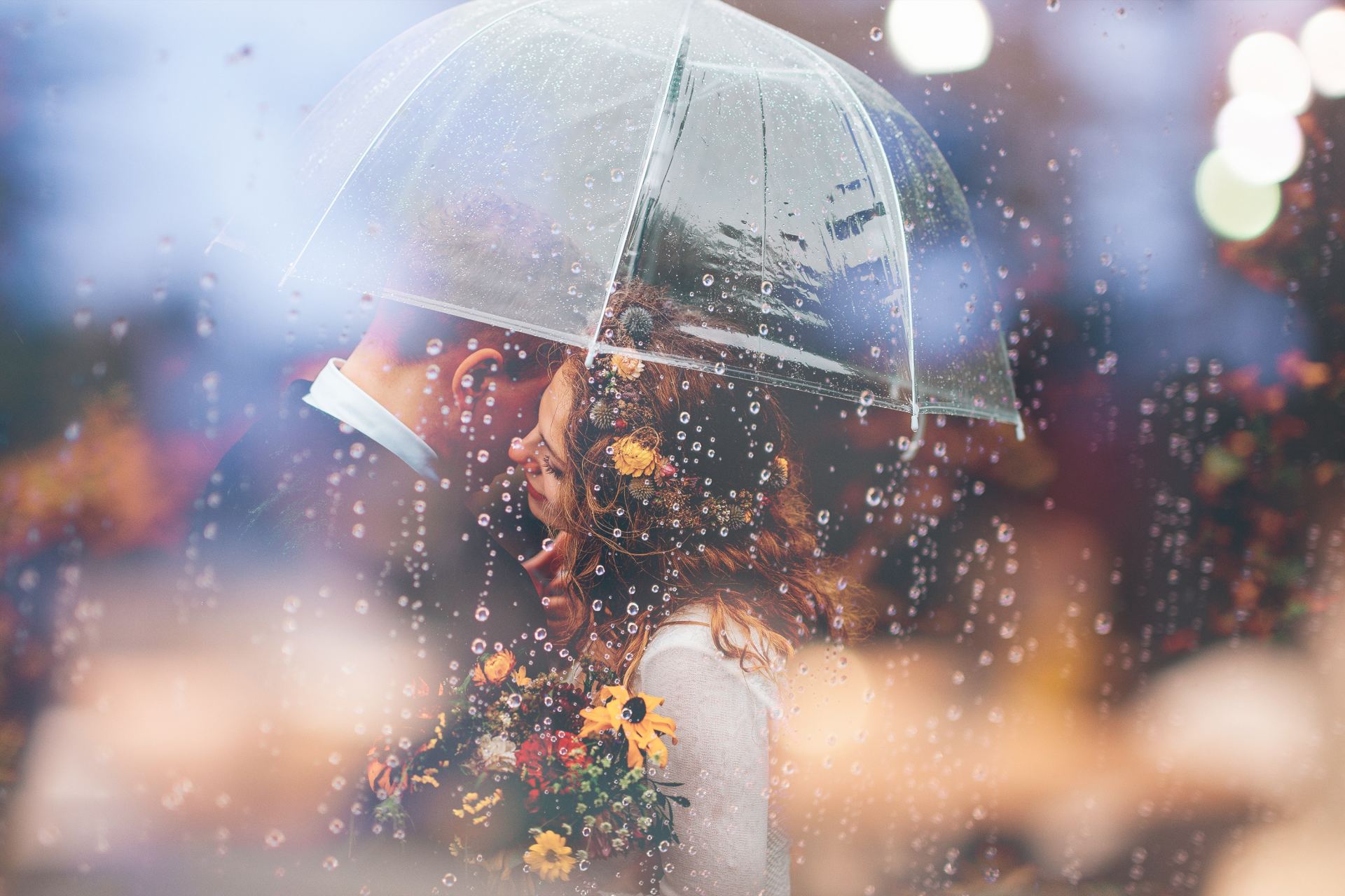 bridal couple with flowers dance under umbrella at their rainy Noosa wedding