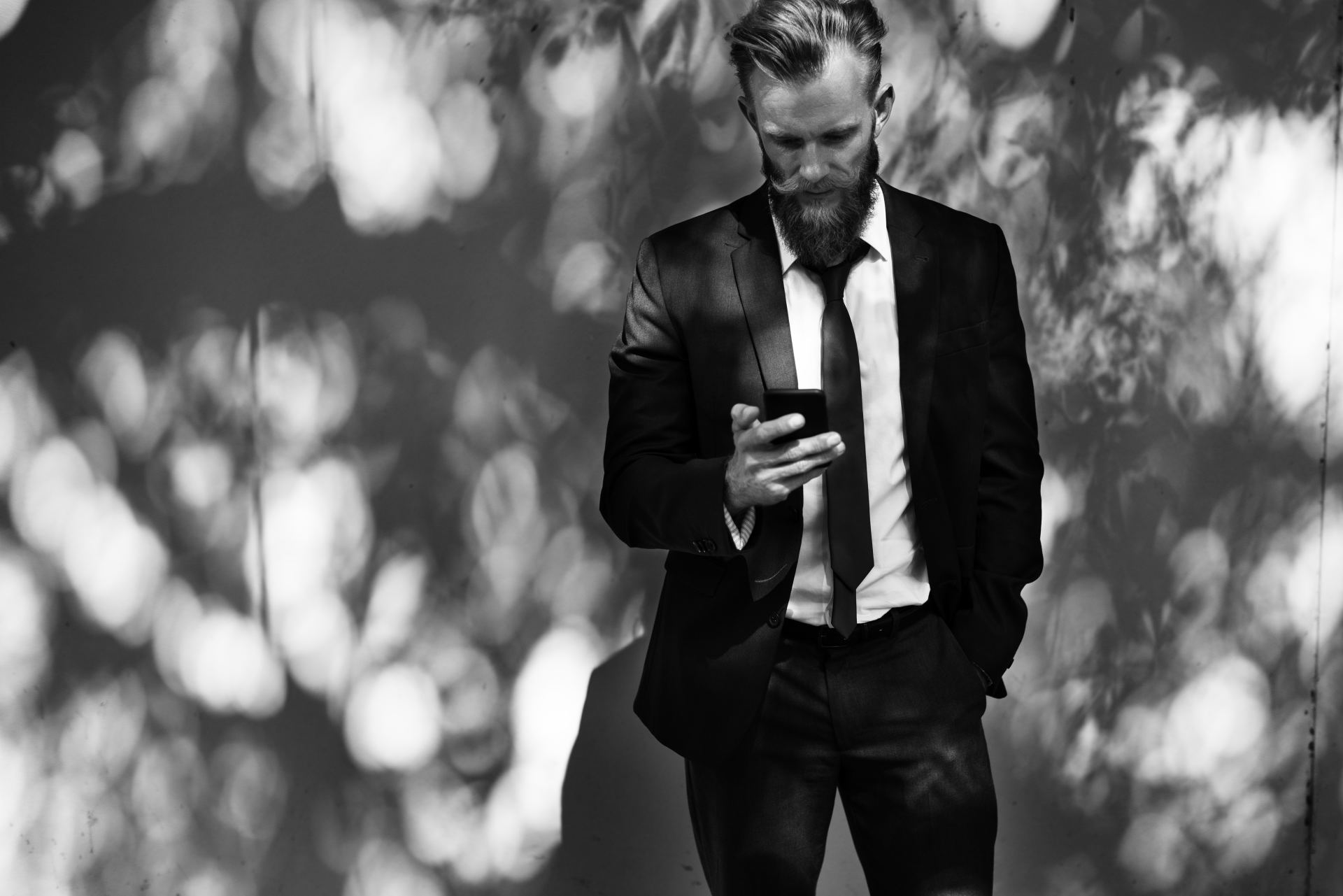 guy looking at his phone searching up information, wearing suit, hand in pocket