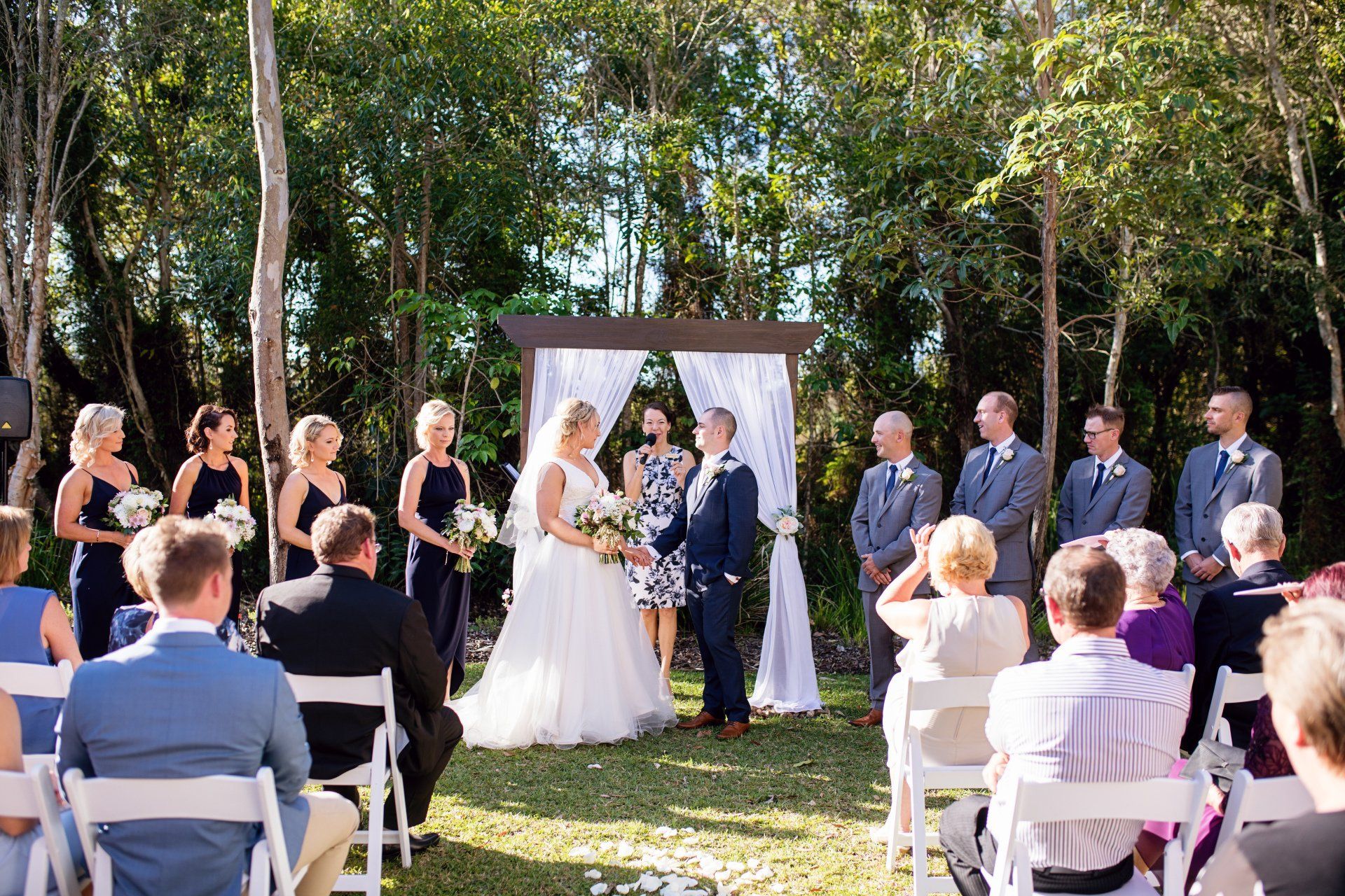 bridal couple and bridal party with celebrant marrying them at RACV Noosa, lots of flowers