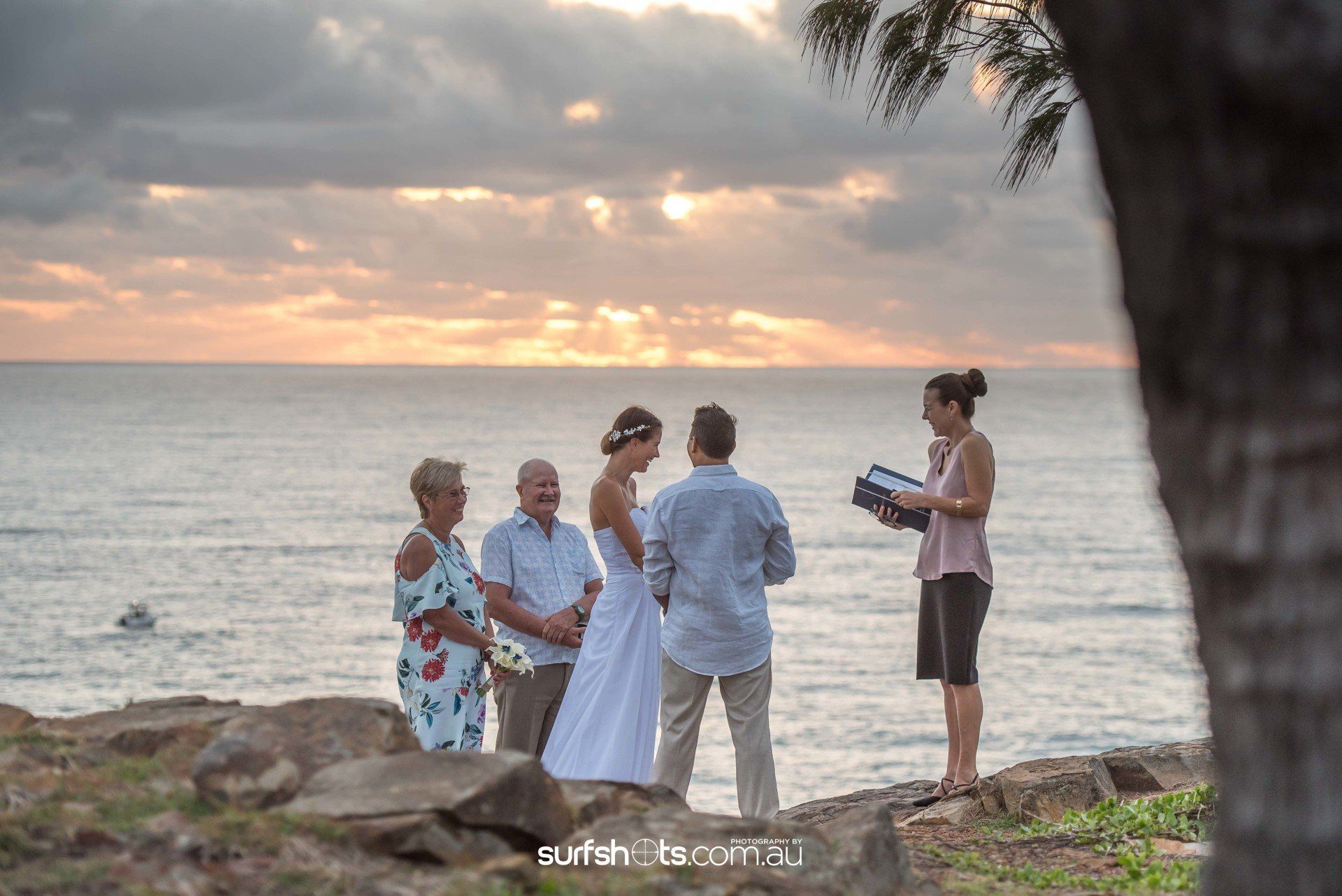 Dawn elopement as the sun is rising with bridal couple and their parents in Noosa National Park, celebrant laughing