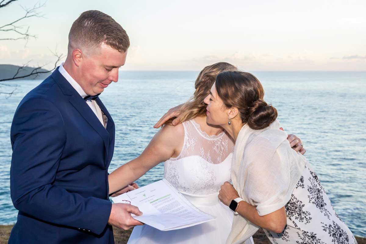 bride kissing her noosa celebrant standing with groom after their Noosa elopement at sunrise on a mountain