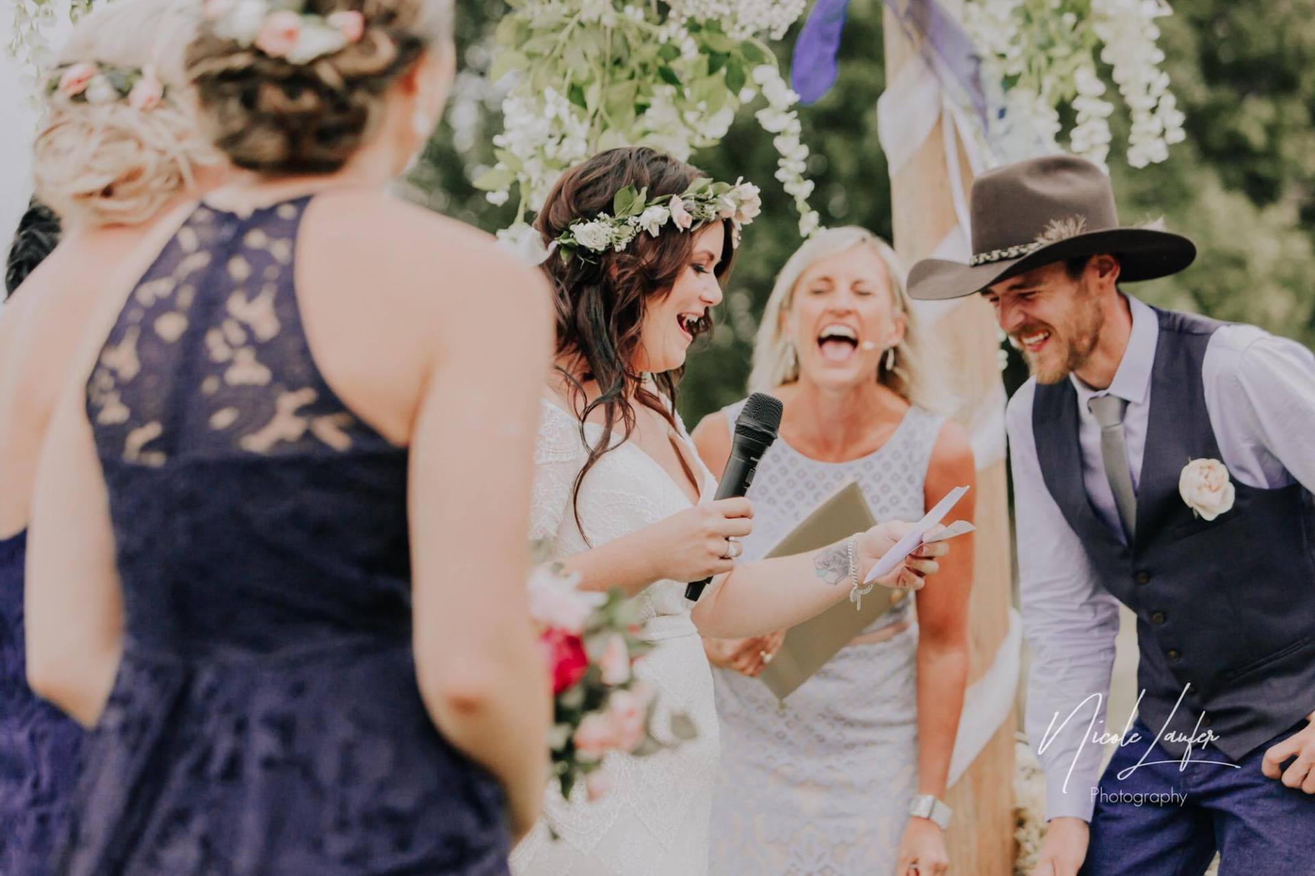 bride in white with flowwer crown laughing at funny wedding vows, groom in cowboy hat and blue waistcoat