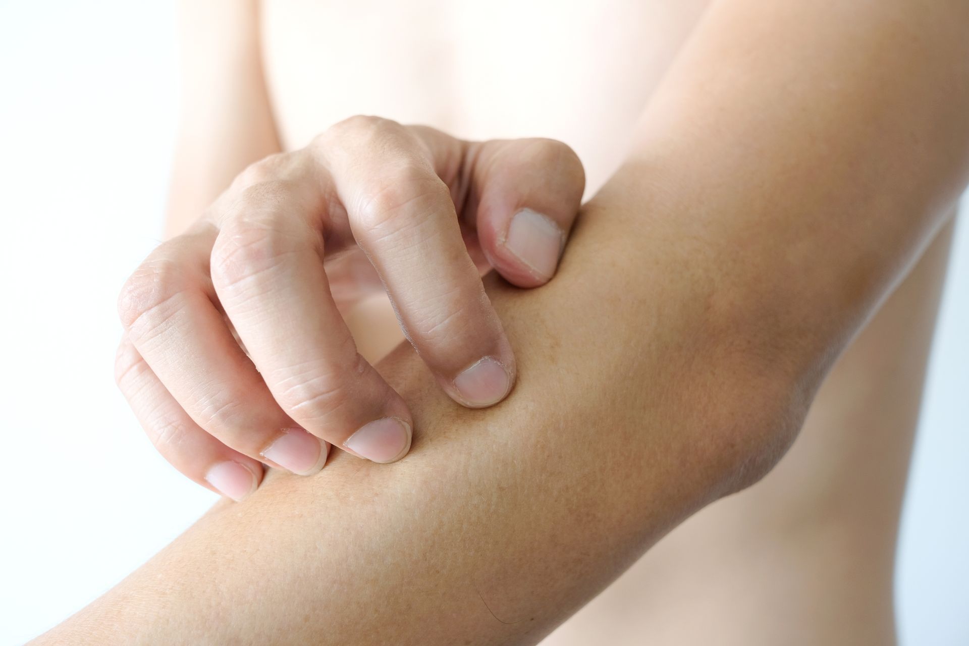 Person scratching their inner elbow. Light skin tone, white background.