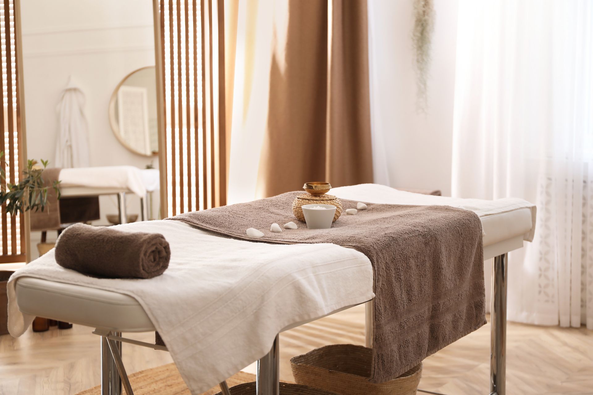 Massage table in a spa setting, with brown towel, decorative items, and a mirror.