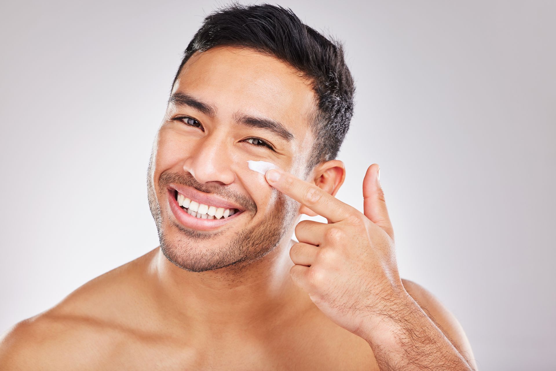 Woman with clear skin, smiling, hand near face.