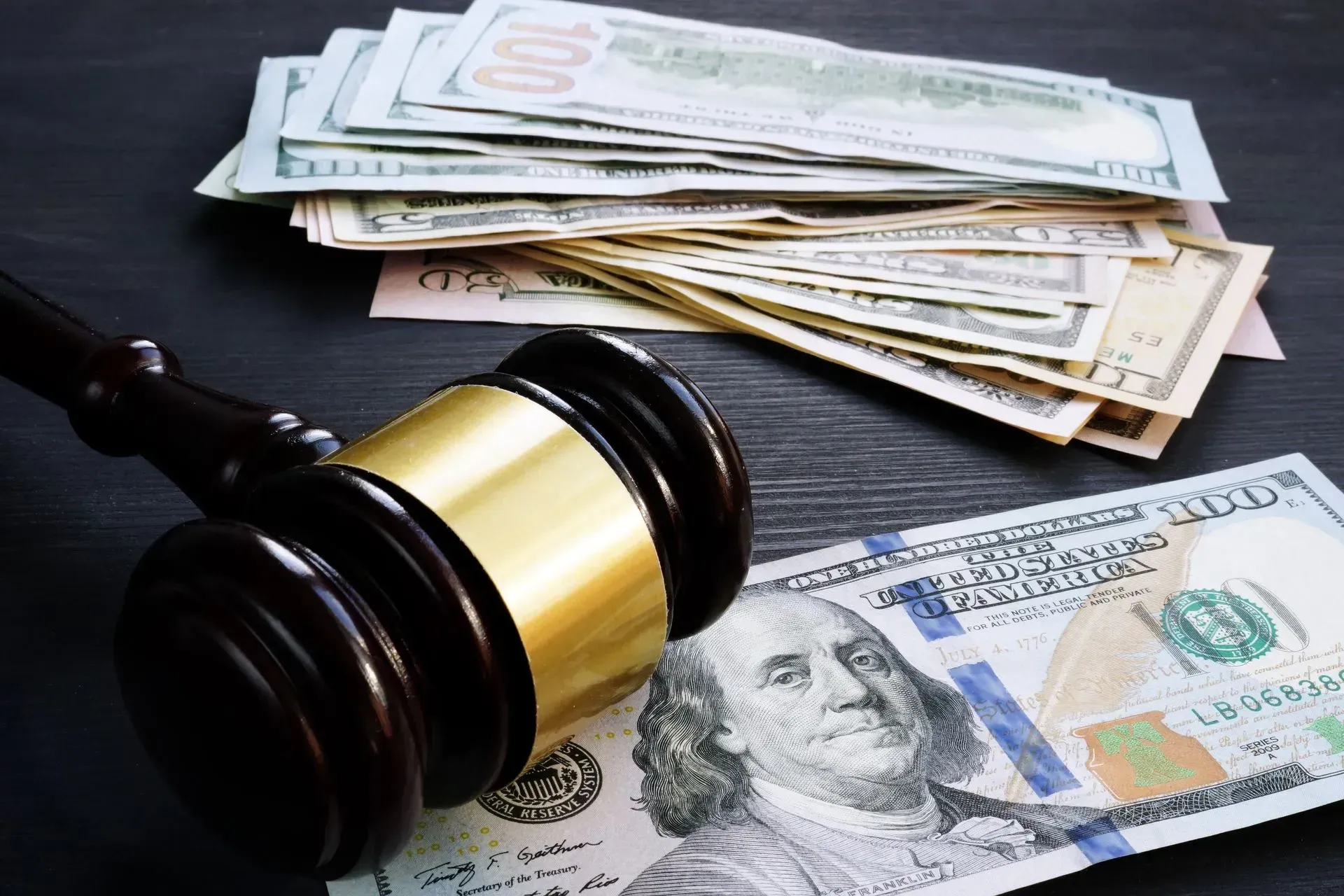 Judge’s gavel beside stacks of cash and a banknote, suggesting a legal money case