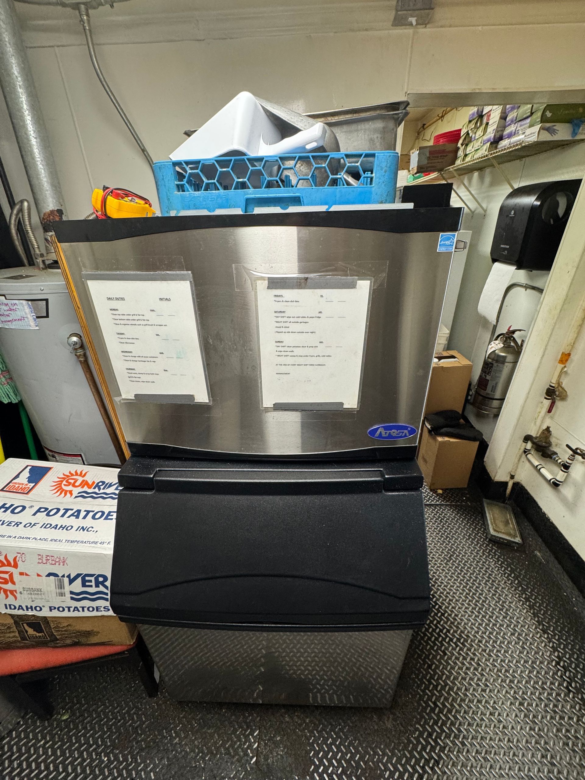 A stainless steel ice machine is sitting in a room.