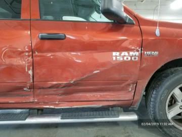 A side view of a red Ram 1500 truck showing significant body damage and a dented passenger door.