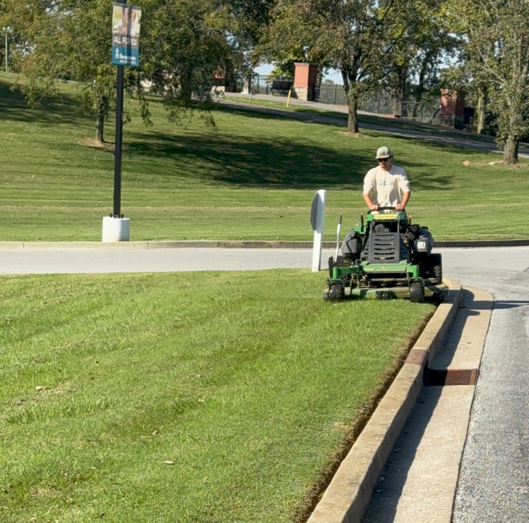 A man is mowing a lush green lawn with a lawn mower.