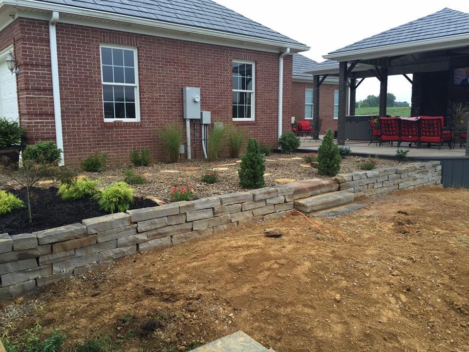 A person is kneeling down and planting plants in a garden.