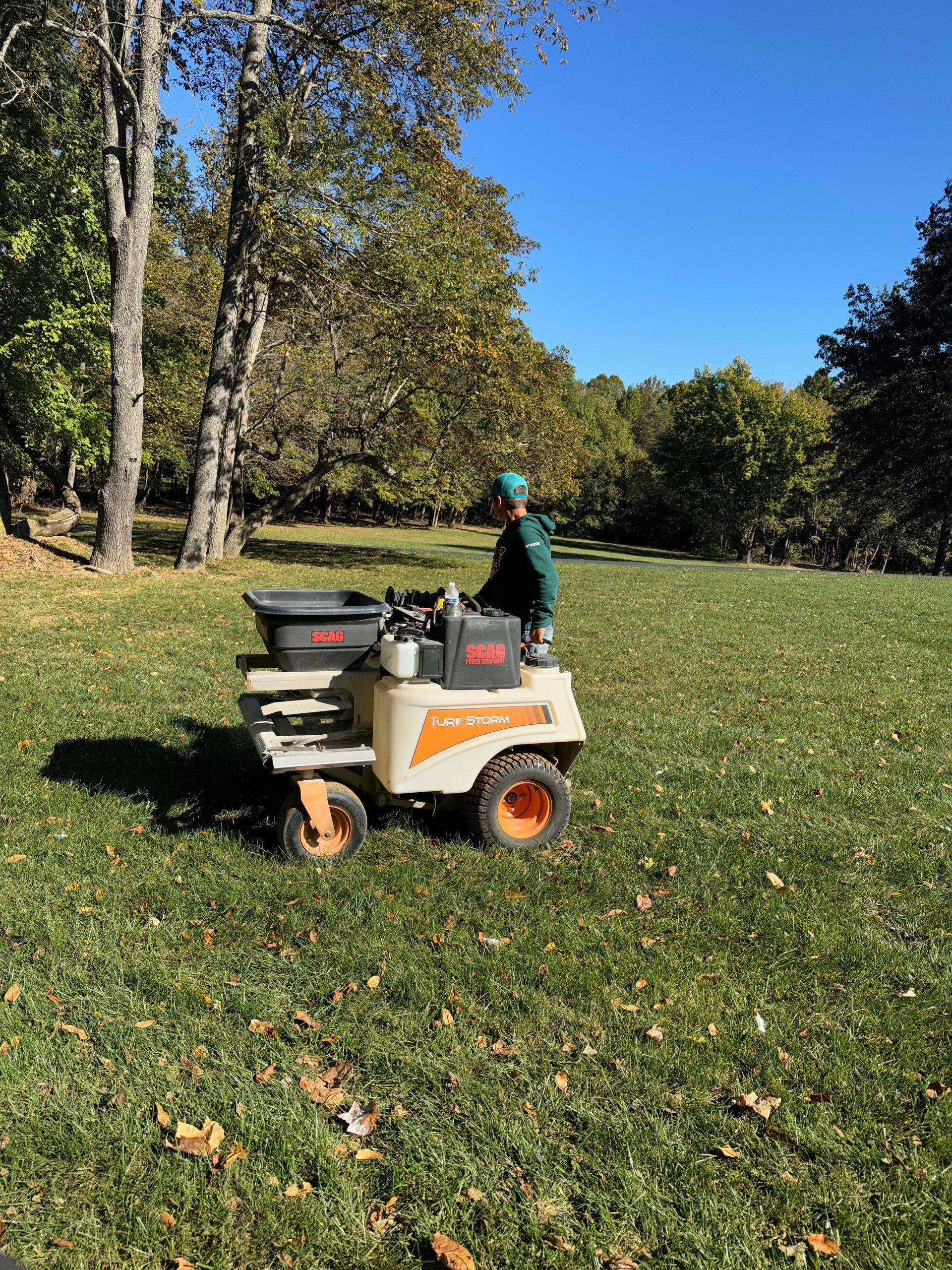A man is rolling a roll of turf in a garden.