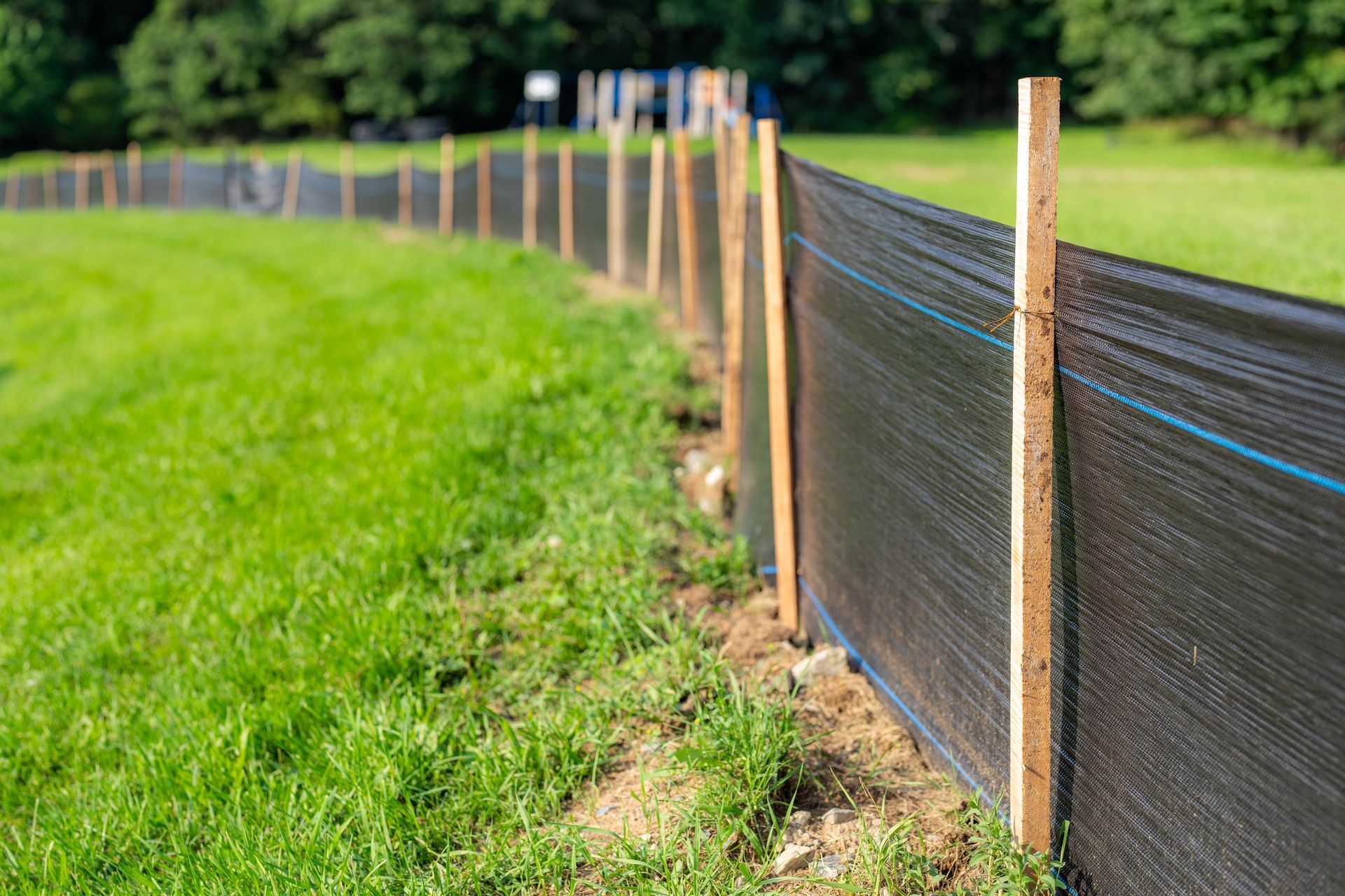 A black fence is being built in a grassy field.